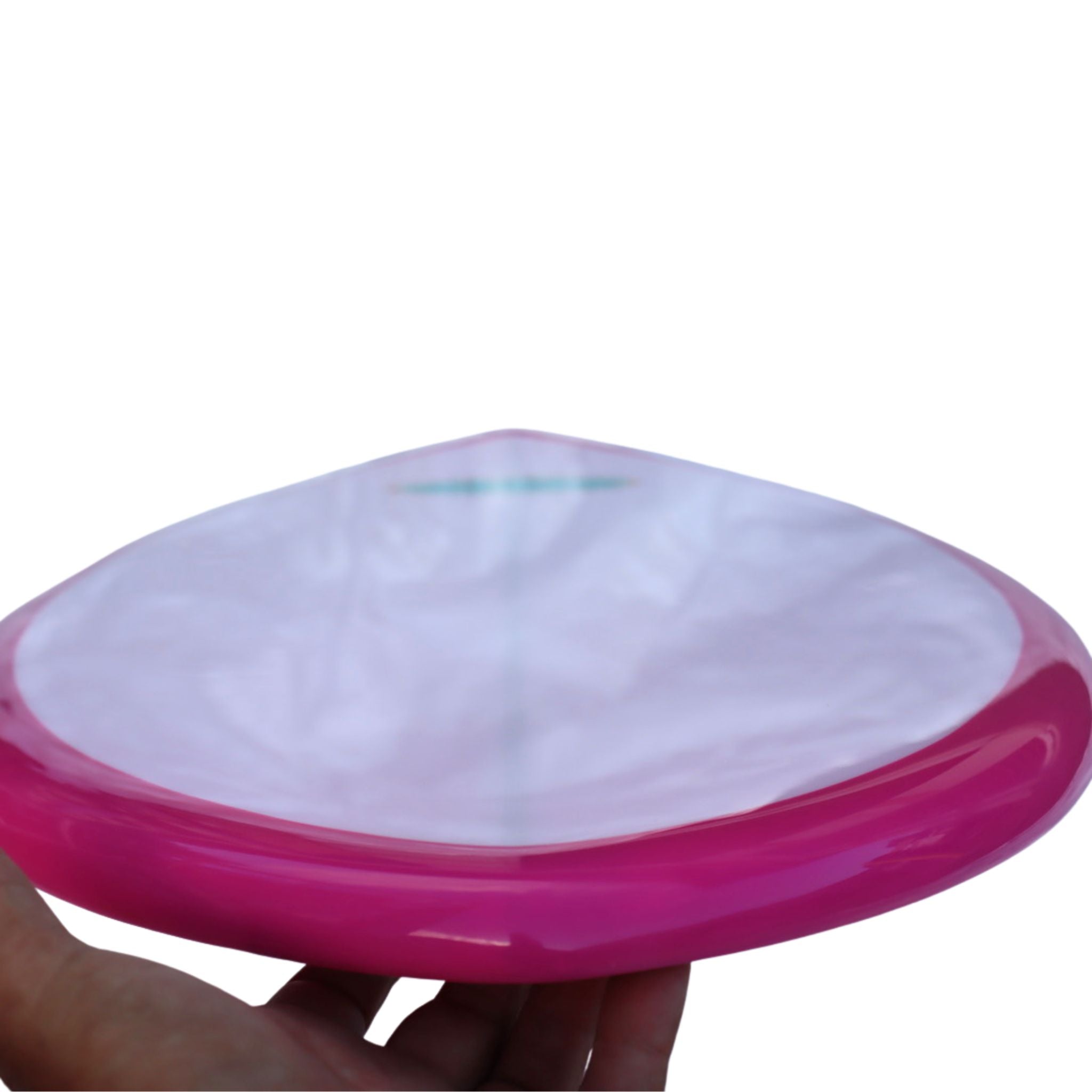 Pink and white skimboard held by a hand on a white background